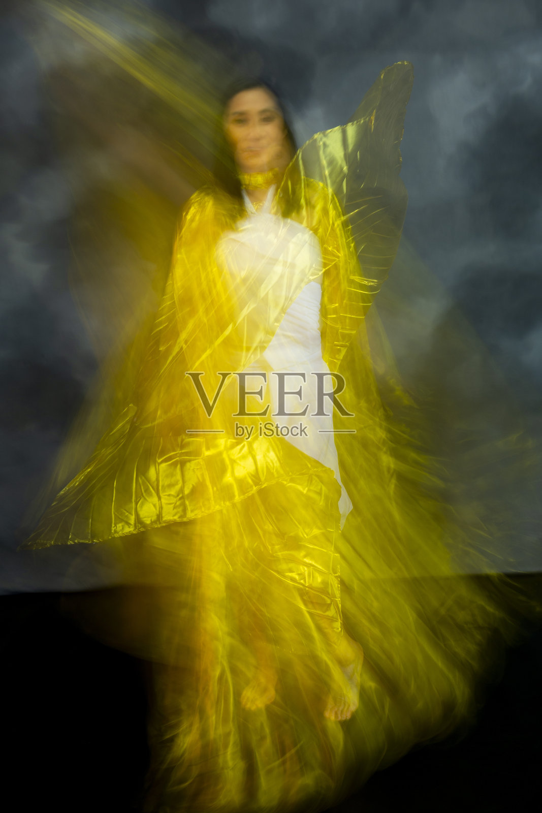 神秘的，模糊的舞蹈照片的成年妇女与金色面料。照片摄影图片