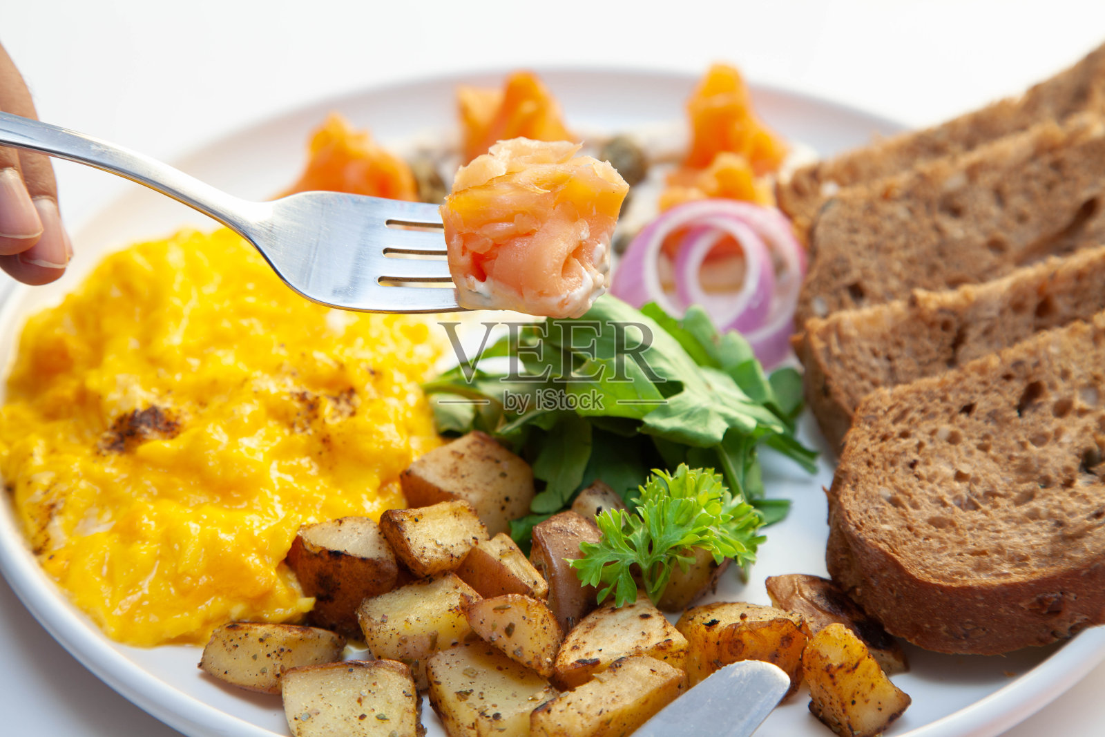 烟熏三文鱼配莳萝奶油酸豆炒蛋配黑麦面包和蔬菜。照片摄影图片