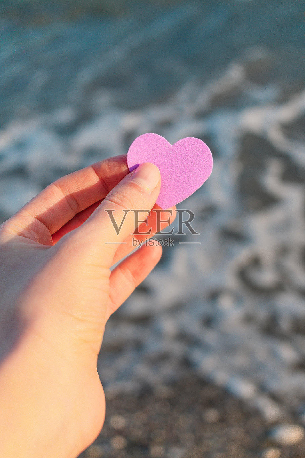 少女手中的紫丁香心，衬托着波浪的背景照片摄影图片