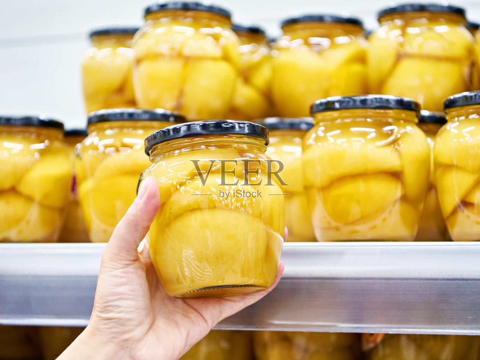 罐头桃子在玻璃罐中，在商店的手照片摄影图片