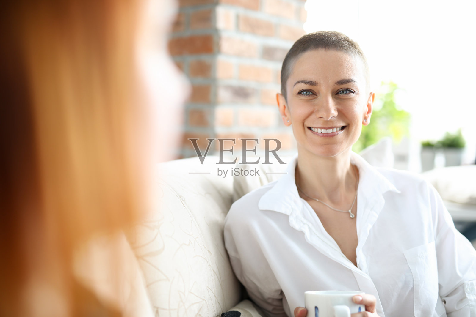 在沙发上微笑的可爱的年轻女子照片摄影图片