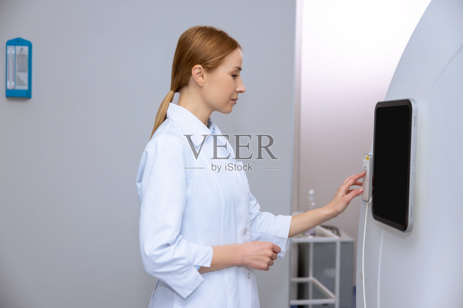 女医生在磁共振成像或计算机断层扫描室使用控制板。照片摄影图片