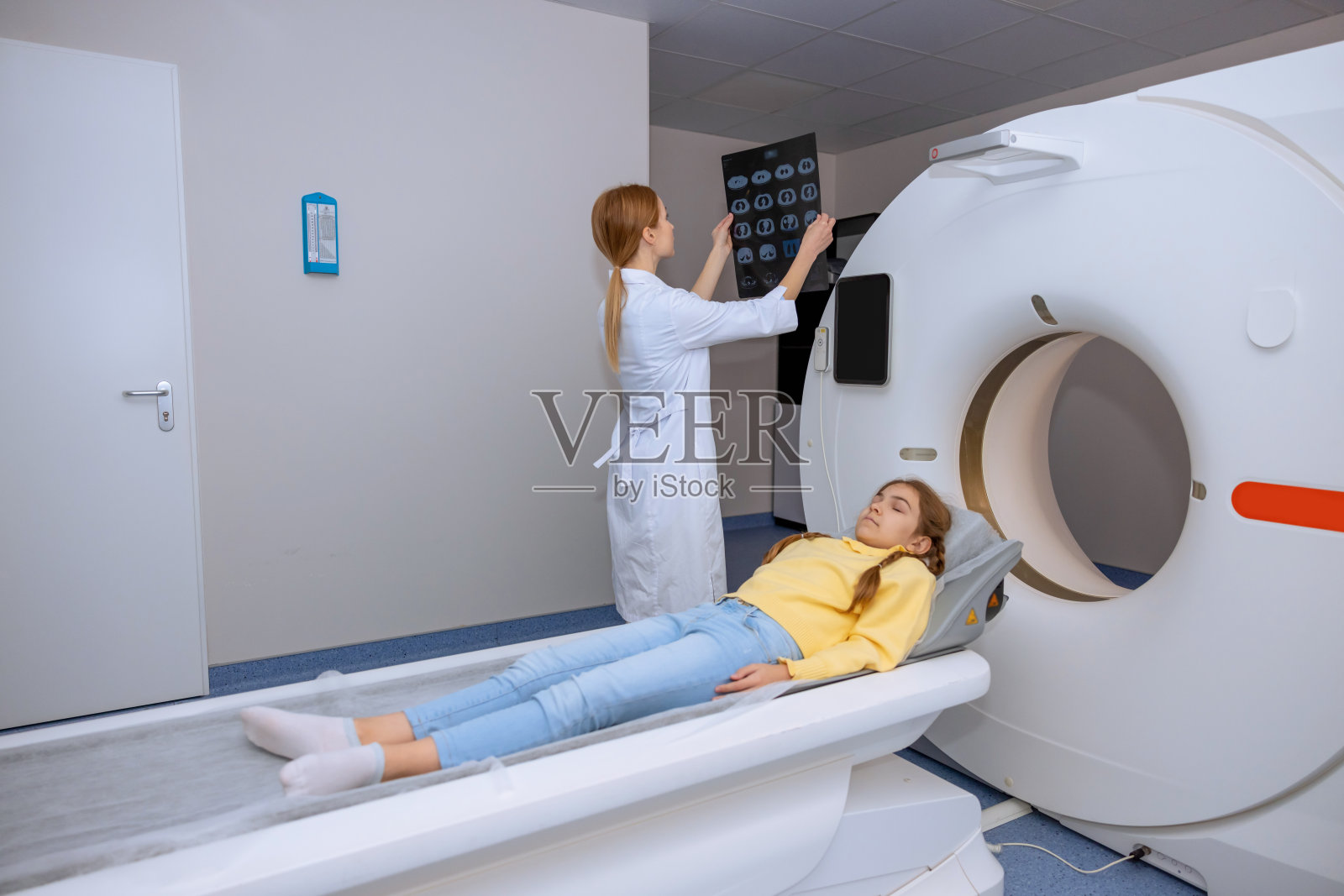 年轻的成年金发女医生在诊所检查核磁共振图像。照片摄影图片