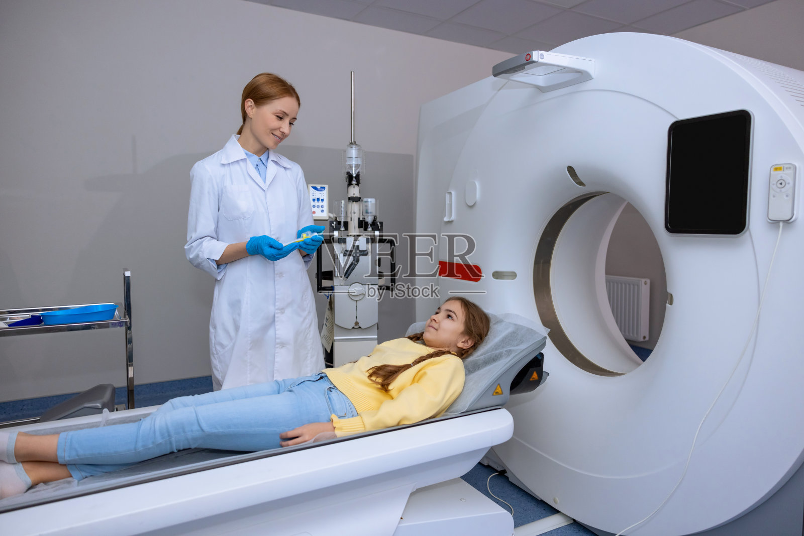 医院核磁共振扫描过程中躺在长长的医疗台上的小病人。照片摄影图片