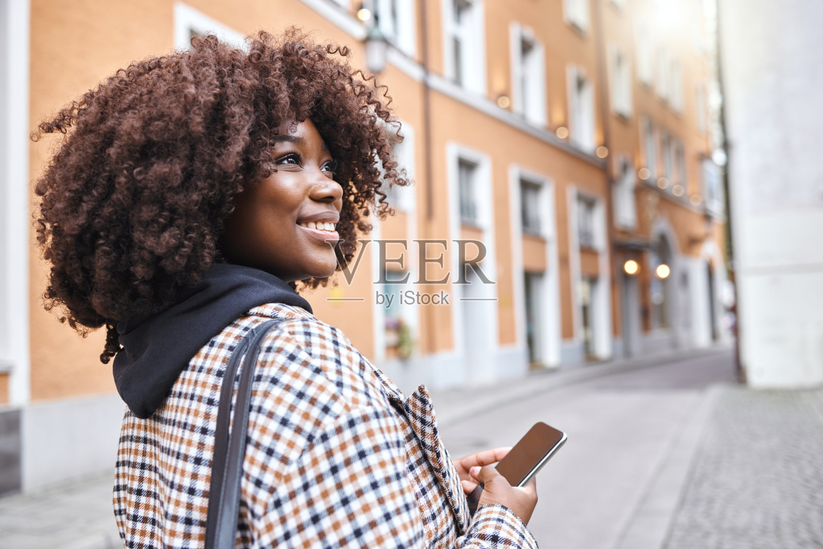 旅行，微笑和黑人妇女在街上拿着电话，在伦敦度假观光，快乐的游客走在路上。假期，城市探险和放松，5g步行与建筑和探索新的城市。照片摄影图片