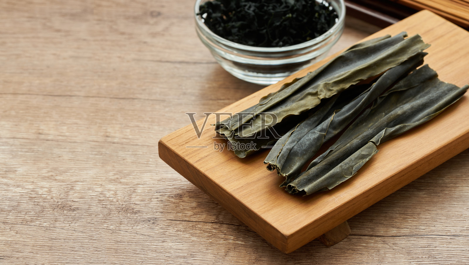 近距离拍摄干海带(海带)木桌背景上木板上的海藻。干海带或海带，背景是木制盘子。昆布，海藻，裙带菜，昆布照片摄影图片
