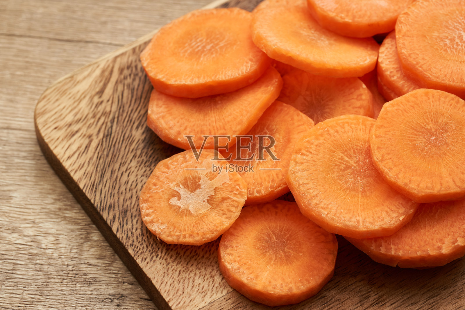 在木桌背景上的木盘上切圆胡萝卜照片摄影图片