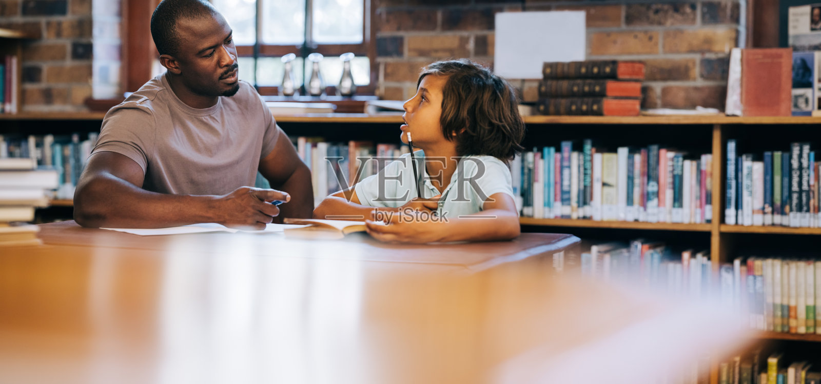 老师在学校图书馆给一个年轻学生辅导照片摄影图片