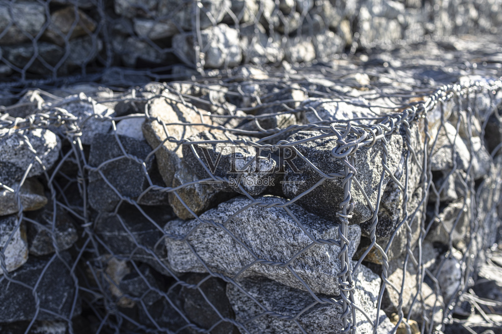 人行道上的金属网里装着石头。照片摄影图片