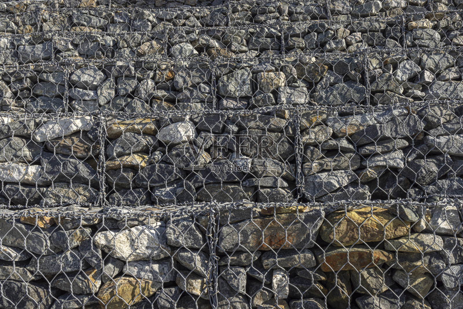 人行道上金属网里的石头，特写。照片摄影图片