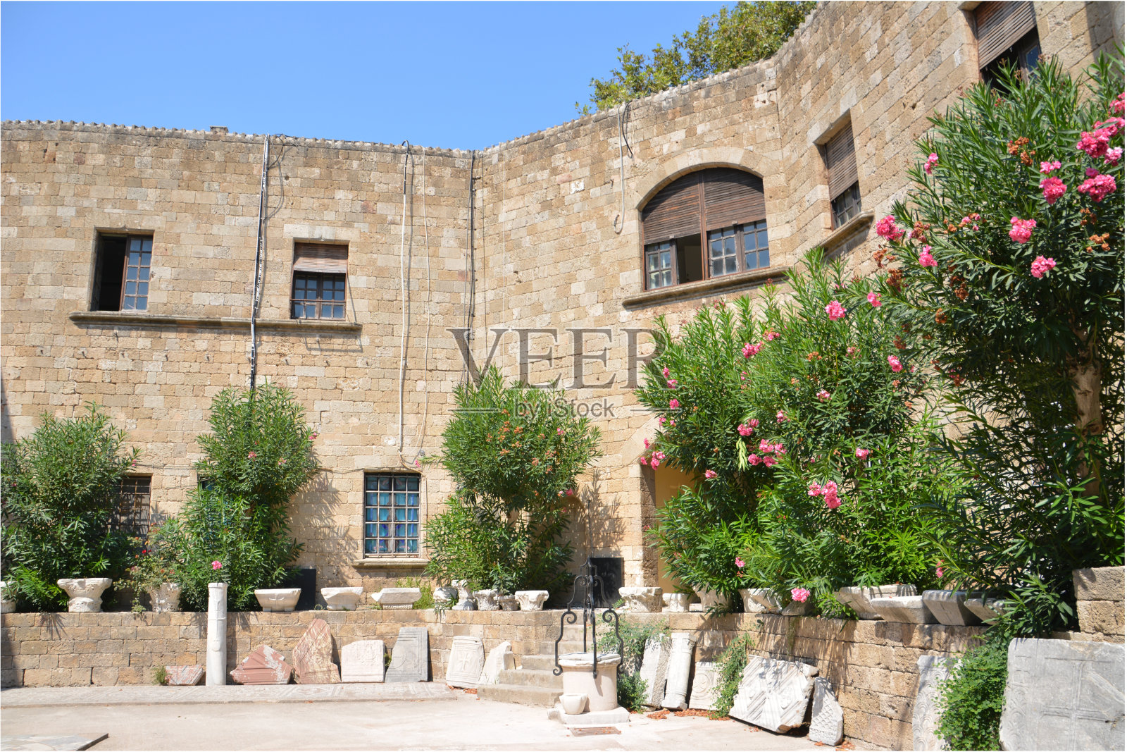 古城堡中的庭院，拱形窗户和前景中的绿树照片摄影图片