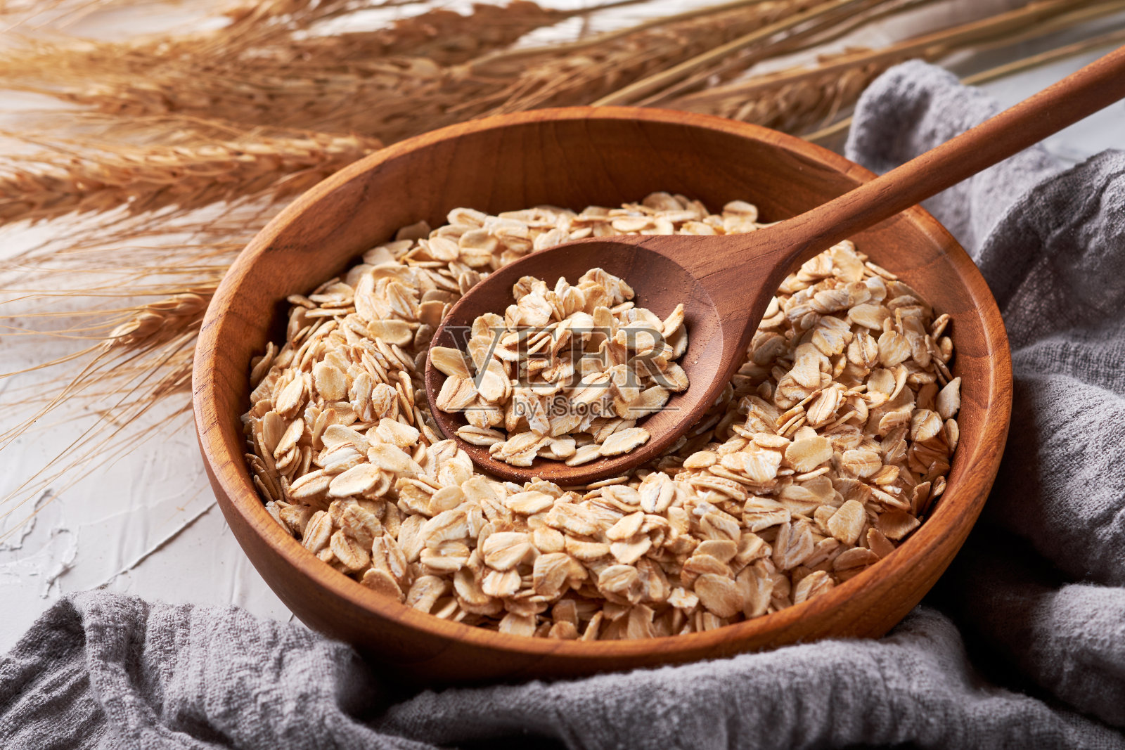 燕麦片或燕麦片装在木勺背景的碗里照片摄影图片