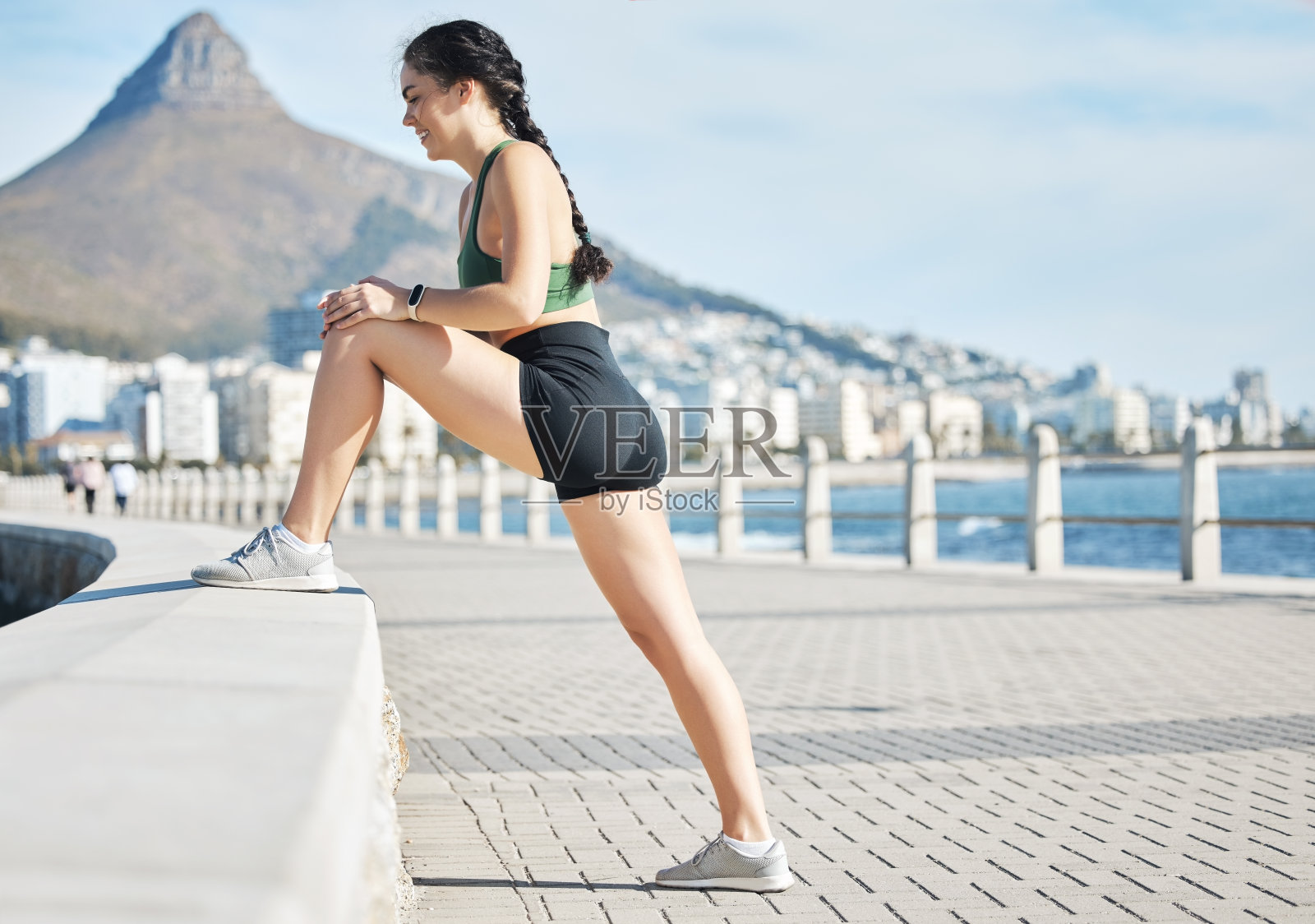 健身，女人和伸展腿在开普敦的海滩跑步，锻炼或有氧运动。活跃的女性跑步者在热身腿部伸展准备跑步，锻炼或训练的性质照片摄影图片