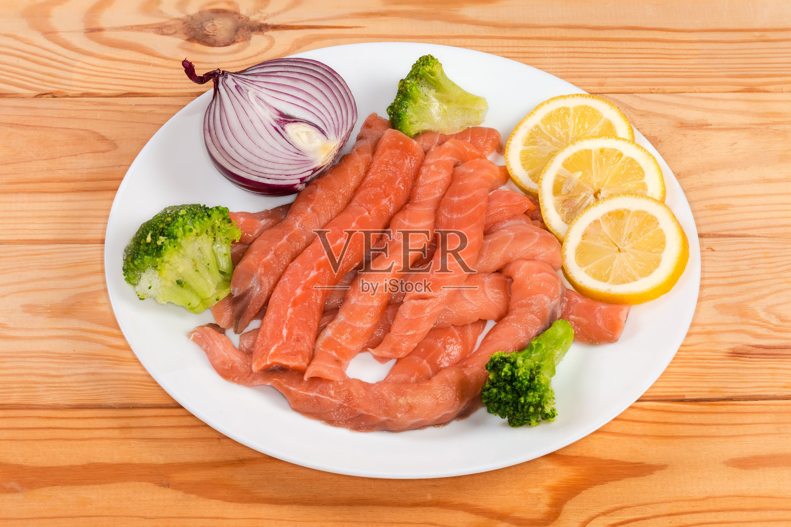 长长的生鲑鱼片夹在蔬菜和柠檬片之间照片摄影图片