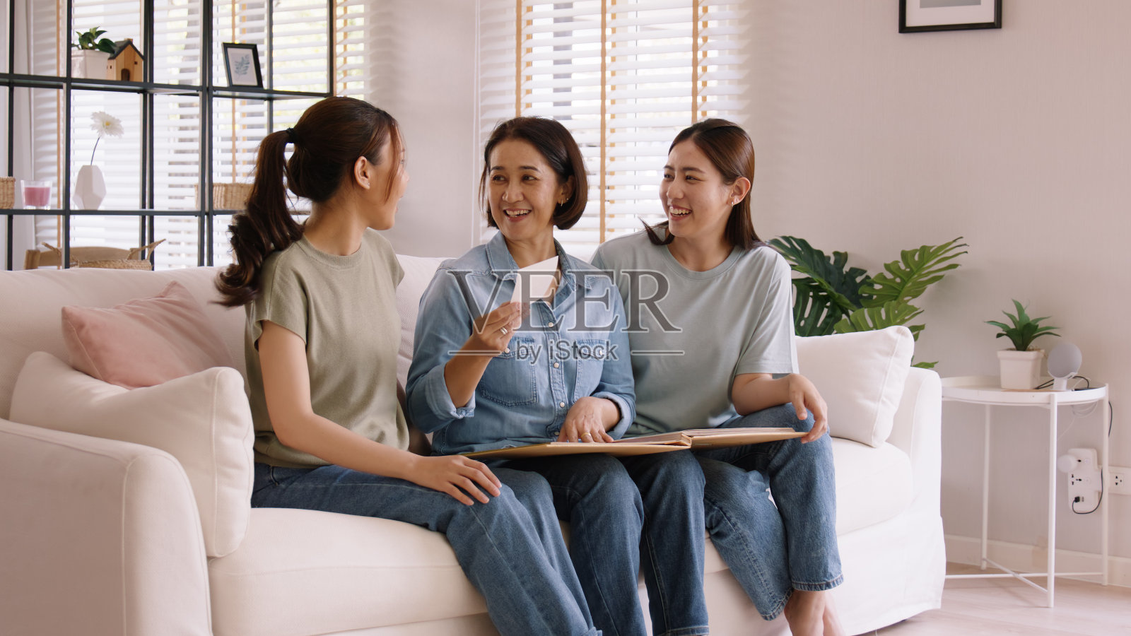 回忆过去的生活回忆快乐的时光母亲节长大的孩子孩子快乐的乐趣看旧的复古相册与成熟的妈妈。亚洲成年人中年妈妈微笑着享受放松地坐在家里的沙发上。照片摄影图片