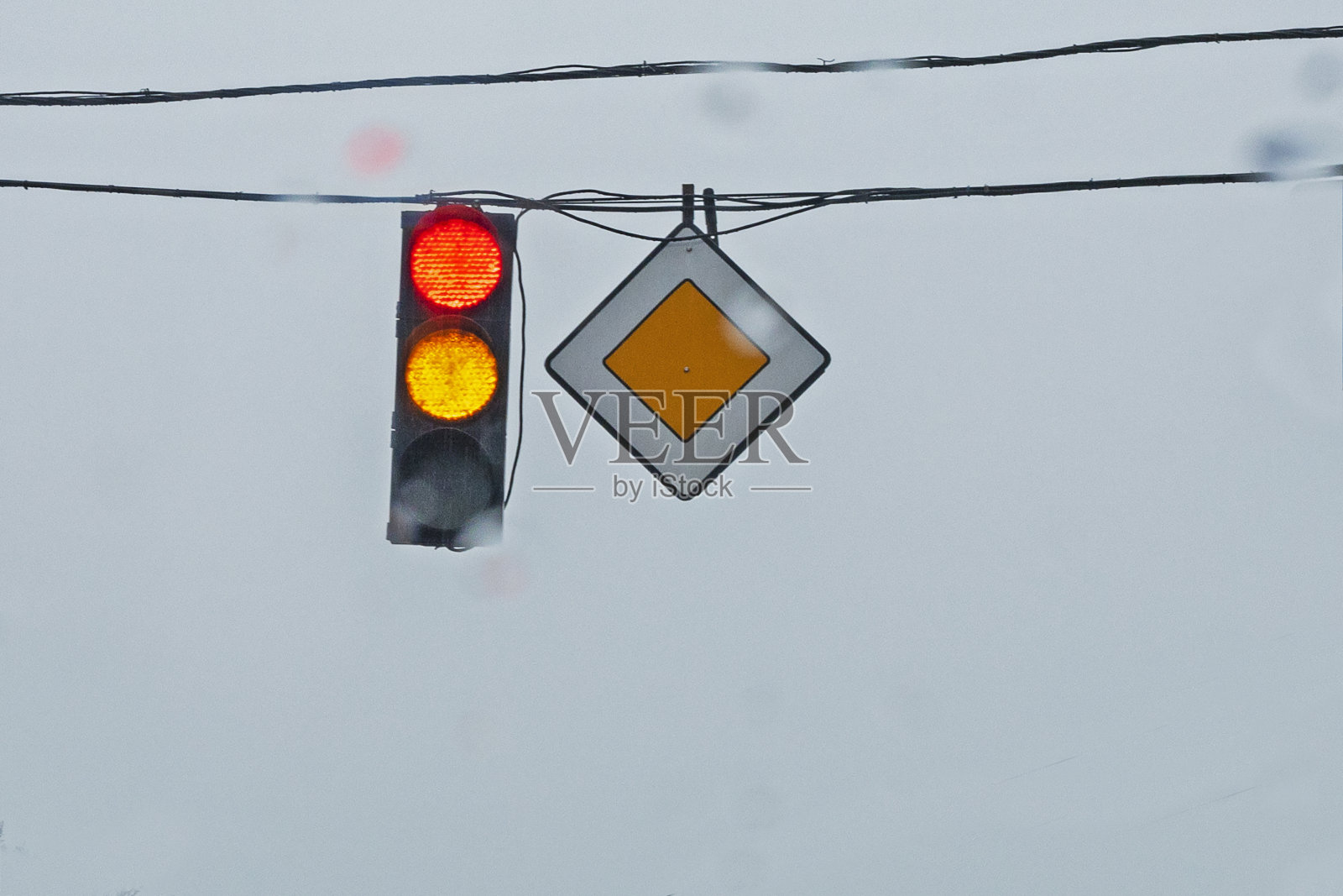 在恶劣天气下，灰色背景上有指向主路的交通信号灯照片摄影图片