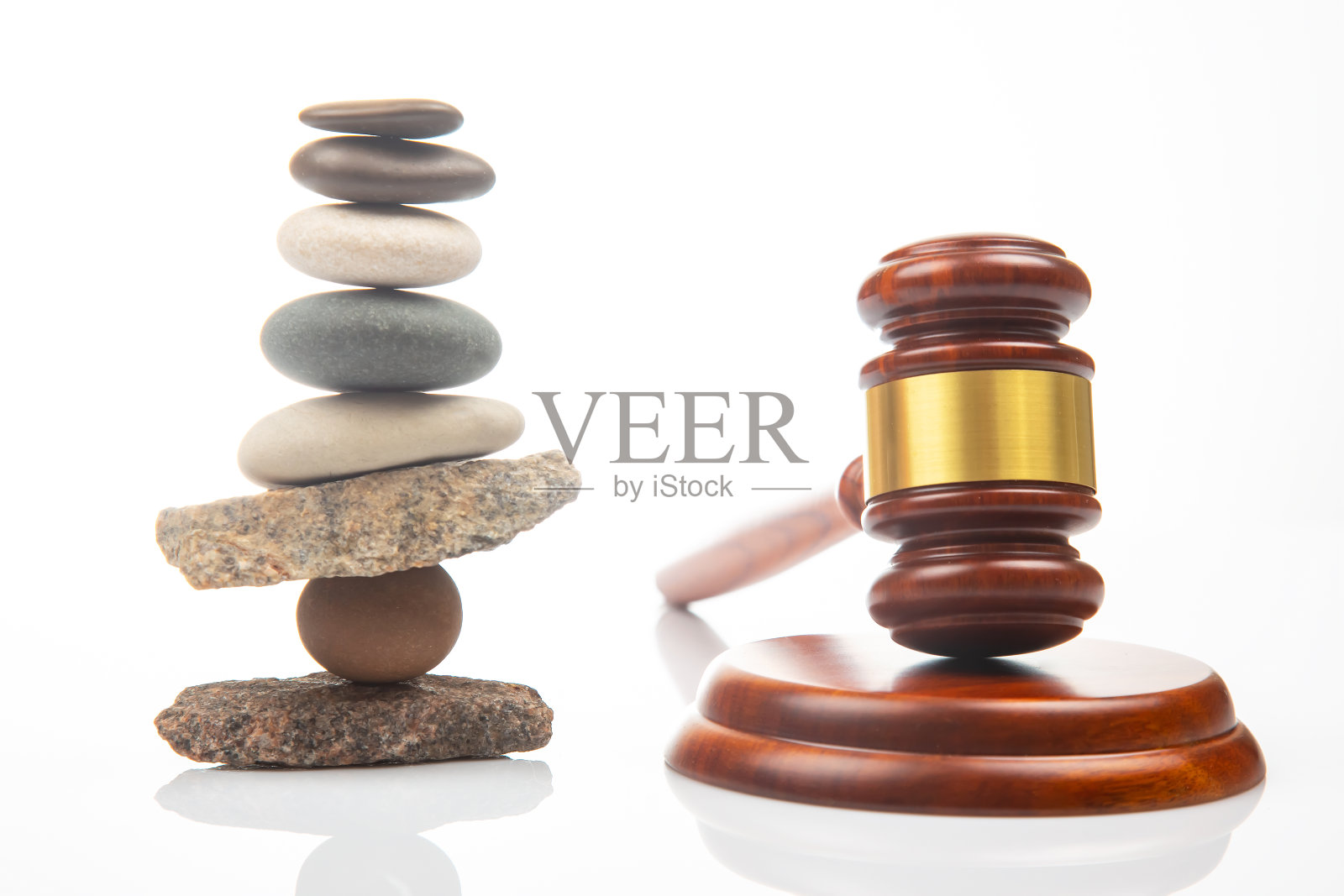 白色背景上堆叠的石头和正义与法律的法槌金字塔照片摄影图片
