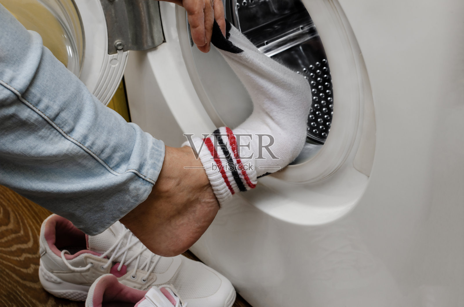 在洗衣机旁边脱袜子的女人照片摄影图片