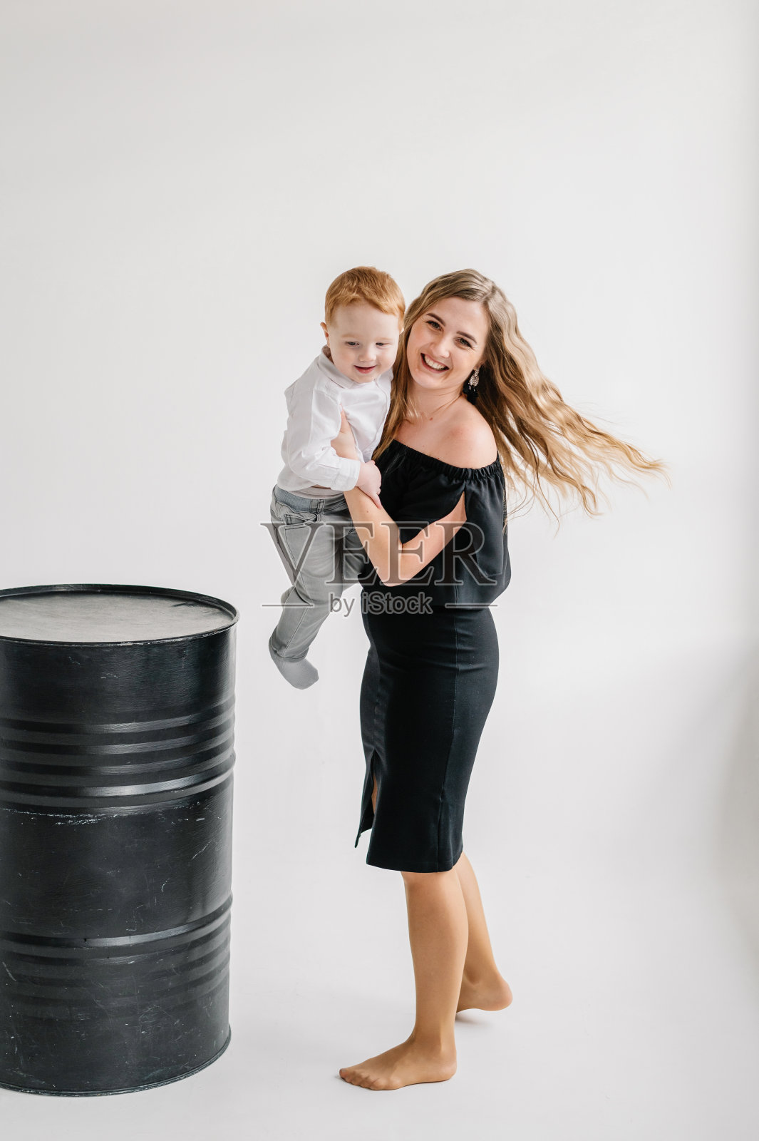 一位年轻快乐的母亲拥抱着孤立在工作室白色背景墙上的孩子。有趣的父母拥抱孩子，和孩子一起玩。妈妈和儿子。特写照片。家庭照相馆肖像。照片摄影图片