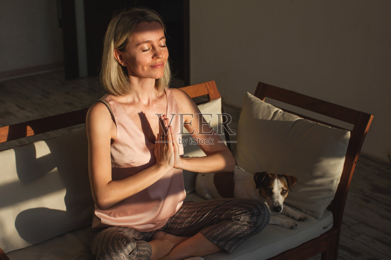 正念的中年妇女坐在家里的沙发上做莲花姿势照片摄影图片