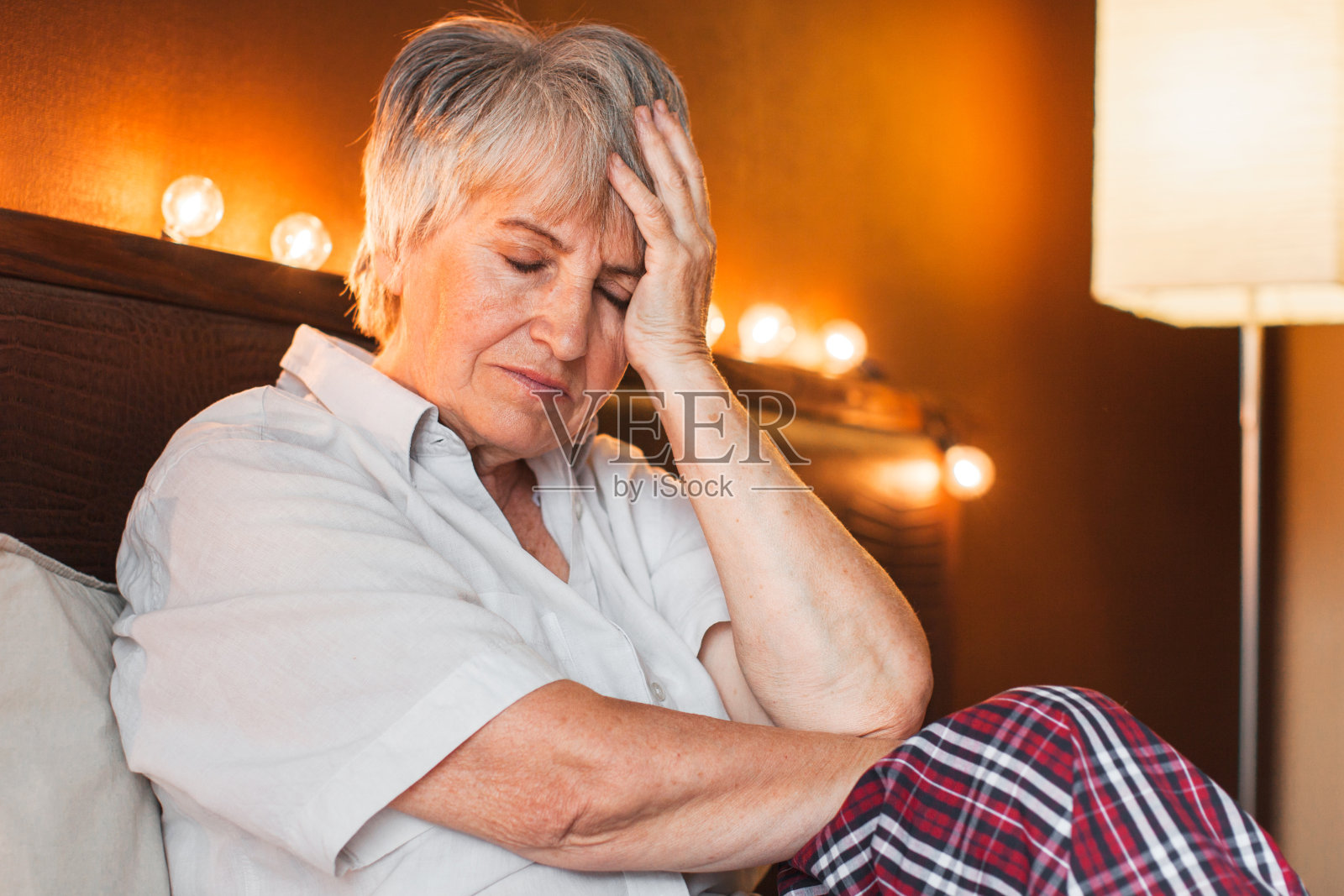 悲伤不快乐的老年妇女坐在卧室的床上照片摄影图片