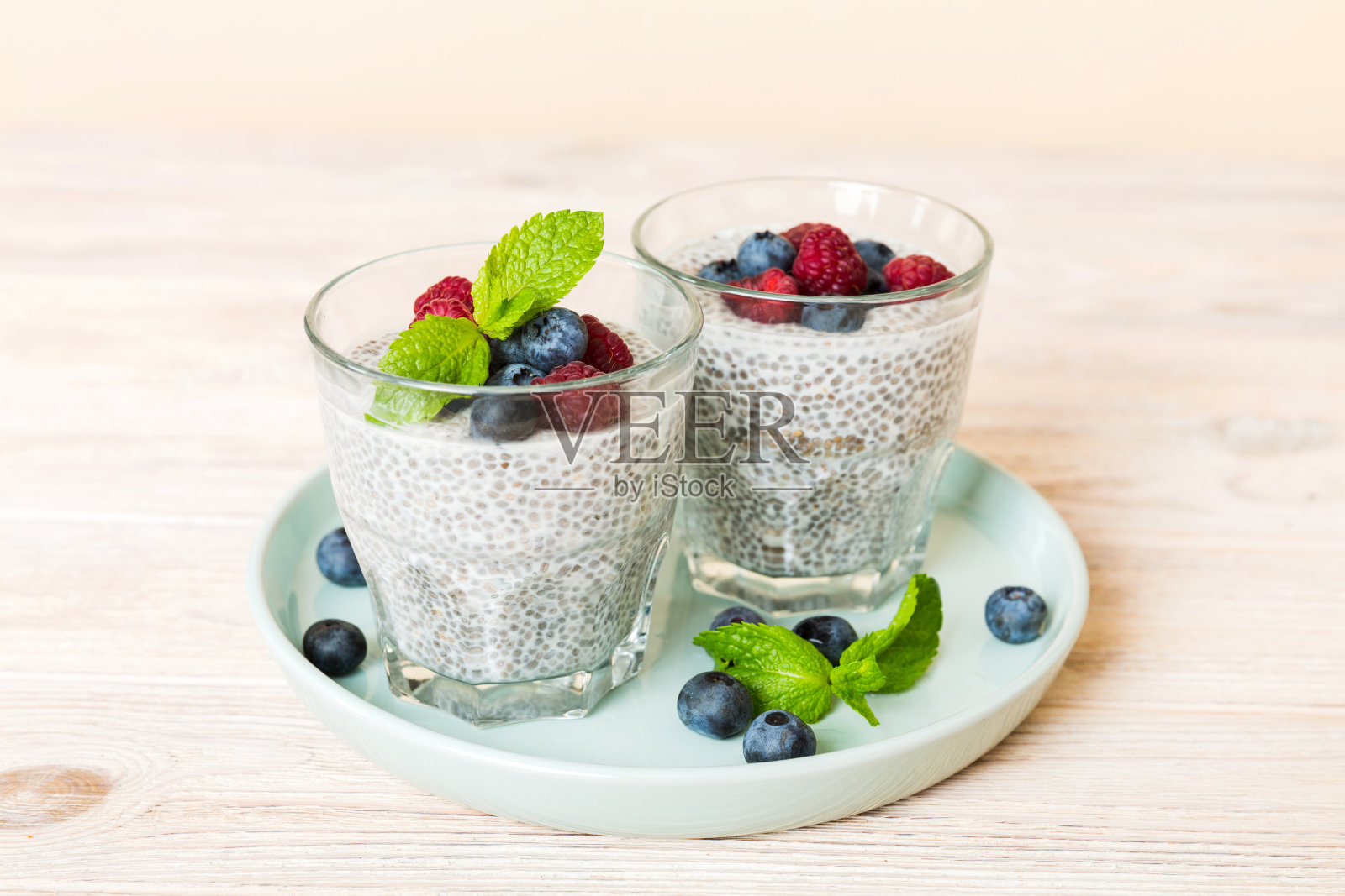 健康早餐或早餐以奇亚籽香草布丁覆盆子和蓝莓浆果为餐桌背景，素食，饮食和健康的概念。覆盆子蓝莓布丁照片摄影图片