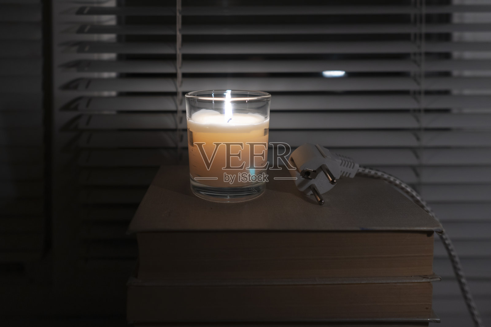 电灯插头躺在一个黑暗的空房间靠窗的蜡烛的光照片摄影图片