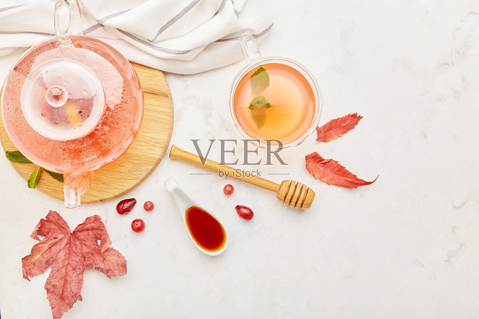 秋季餐桌：玻璃茶壶和有机浆果茶，蜂蜜点缀，留有文案空间照片摄影图片