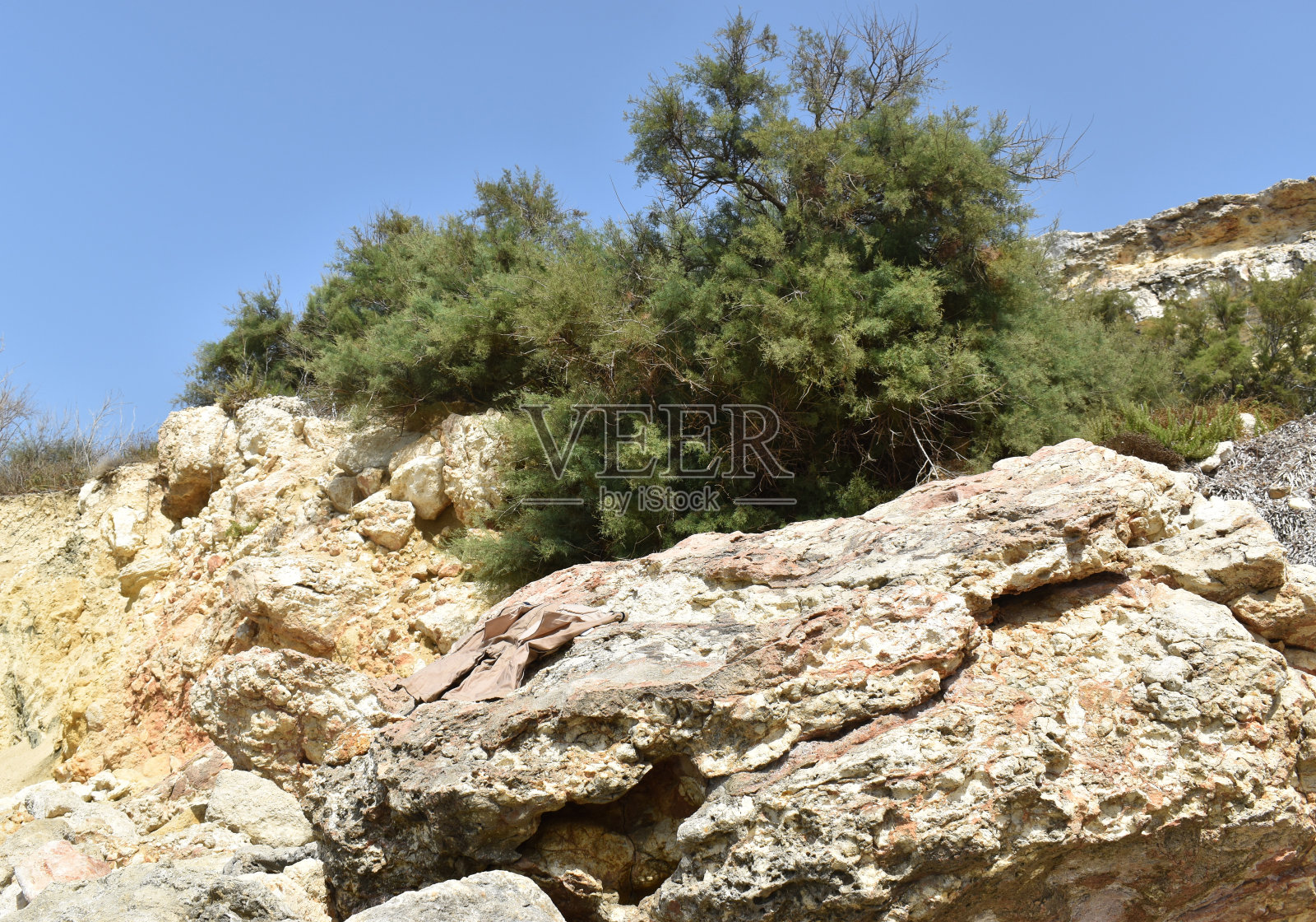 岩石，绿色的灌木丛和蓝色的天空照片摄影图片