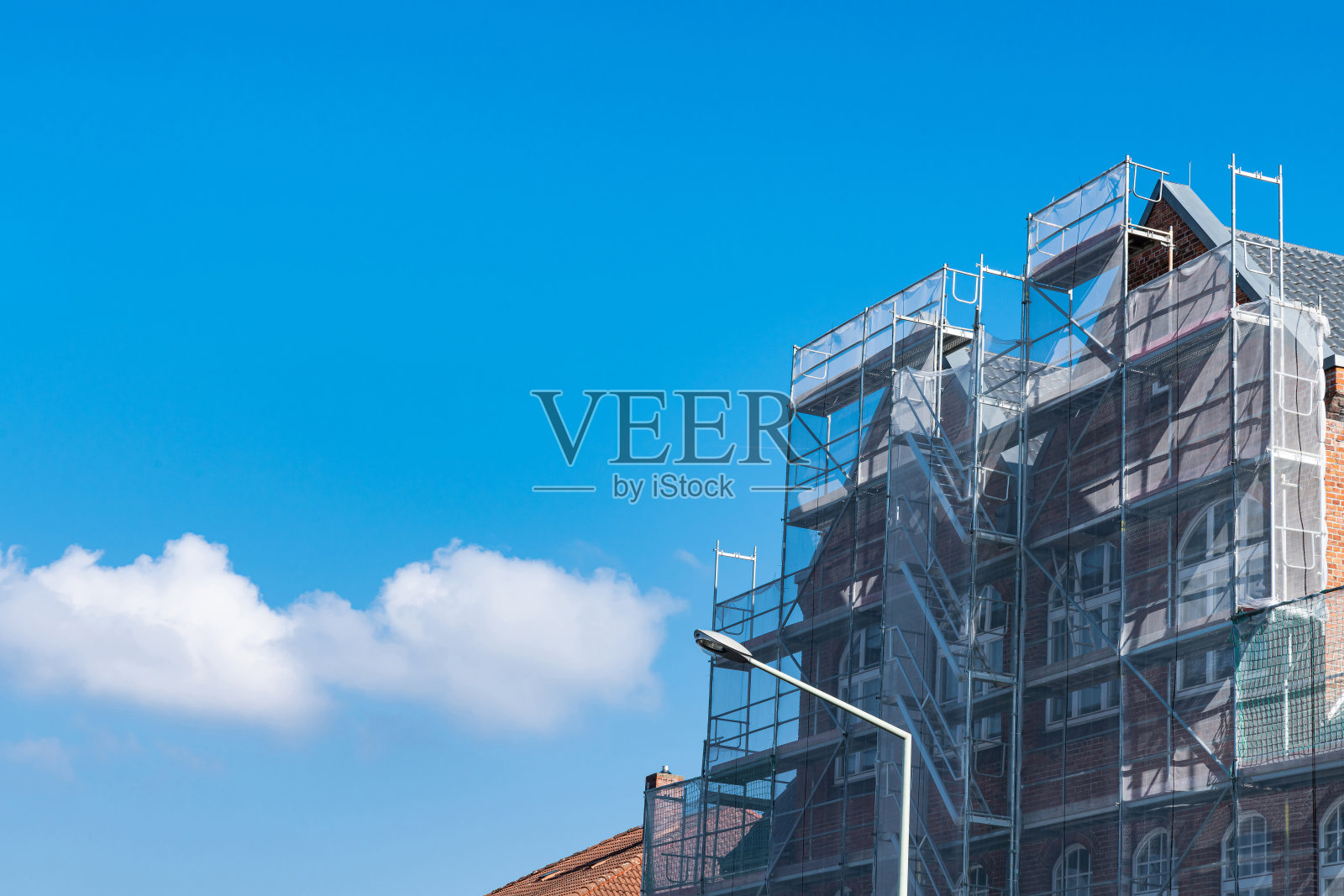 正在修复的建筑物附近，脚手架上覆盖着网。照片摄影图片