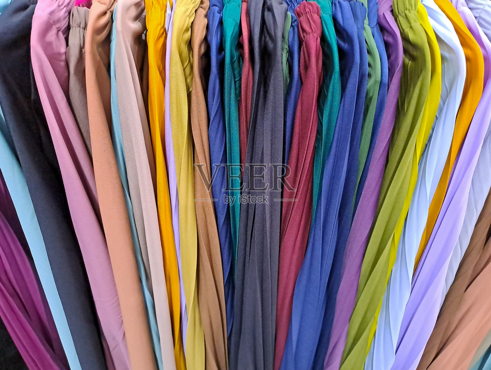 挂在衣柜或衣架上的五颜六色、充满活力的织物。色彩缤纷的衣服背景照片摄影图片