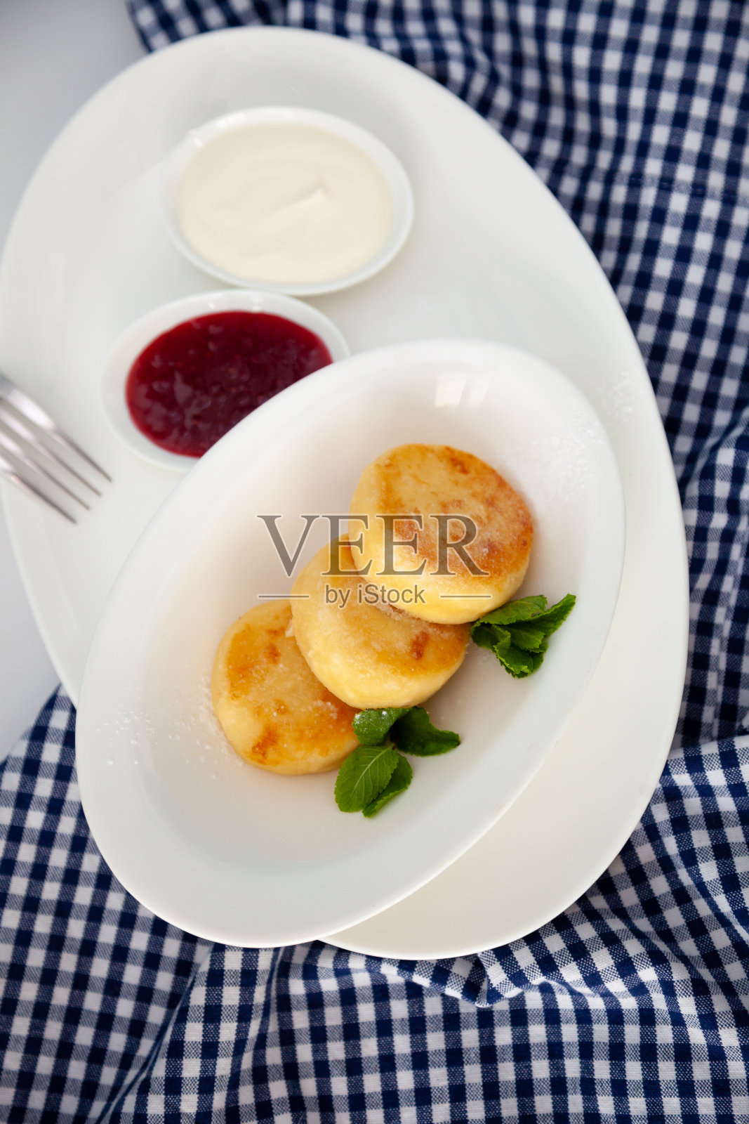 白色盘子里放着蓝色背景的圆形干酪煎饼。早餐的食物。健康食品。照片摄影图片