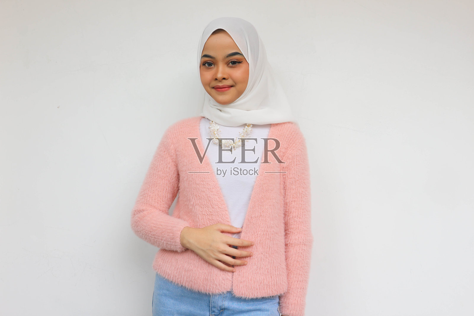 穿着粉红色运动夹克的亚洲美女微笑着把手放在肚子上，在白色背景下吃完美味后感到很饱照片摄影图片