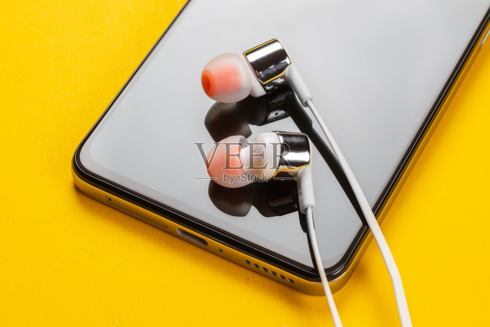 黄色背景的智能手机和耳机。近距离照片摄影图片