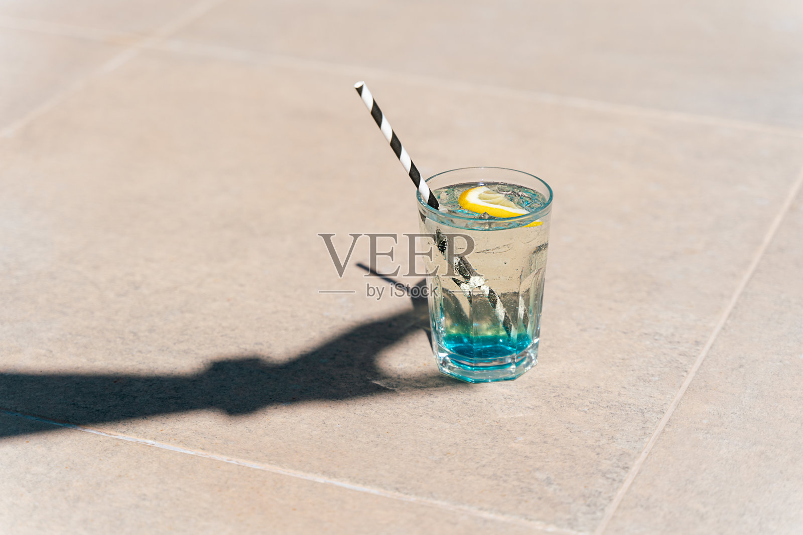 手的影子拿着闪闪发光的薄荷柠檬水热带鸡尾酒从玻璃杯站在大理石地板上的特写镜头。你好，暑假。复制空白照片摄影图片