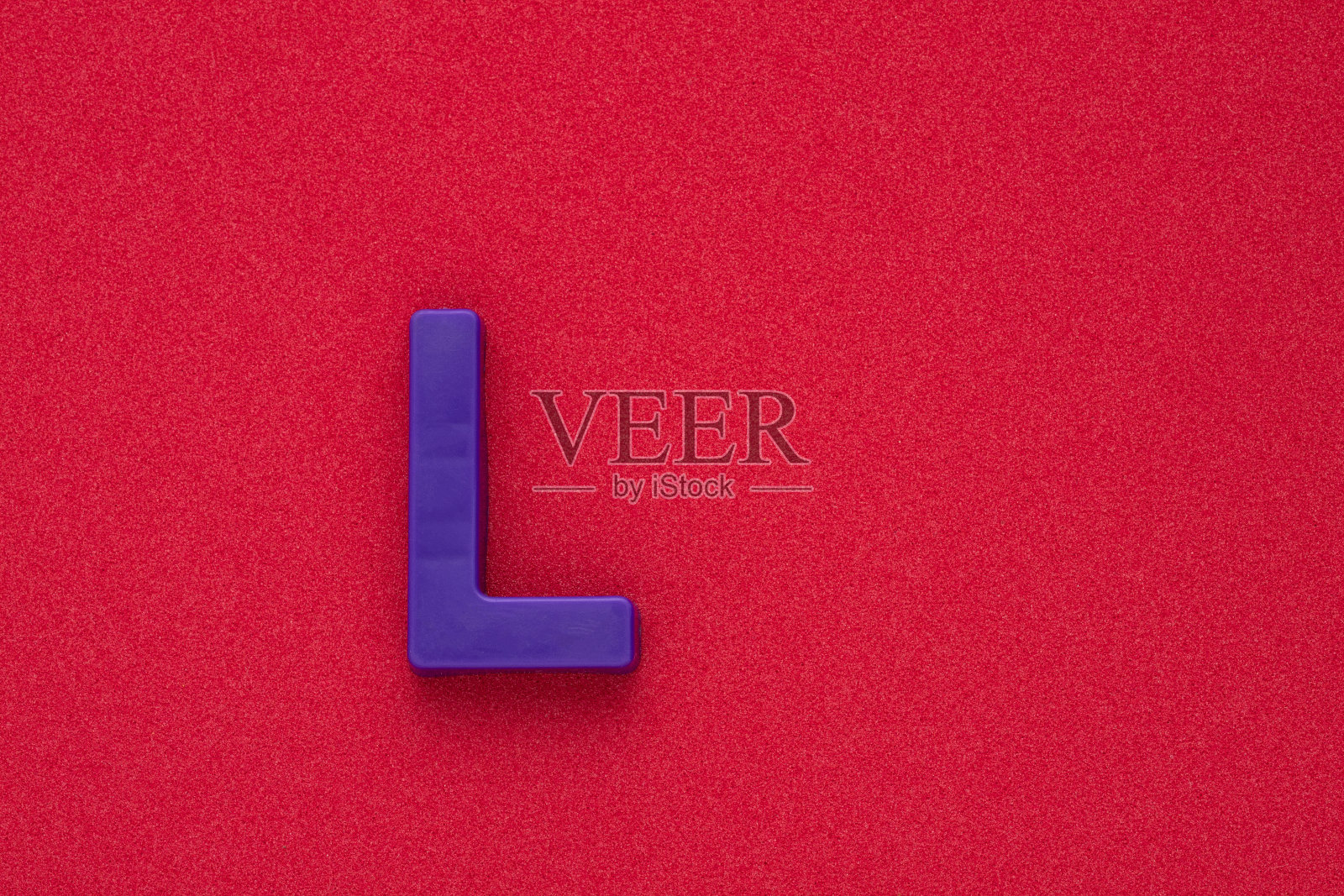 字母L -紫色塑料片在红色032c泡沫背景照片摄影图片