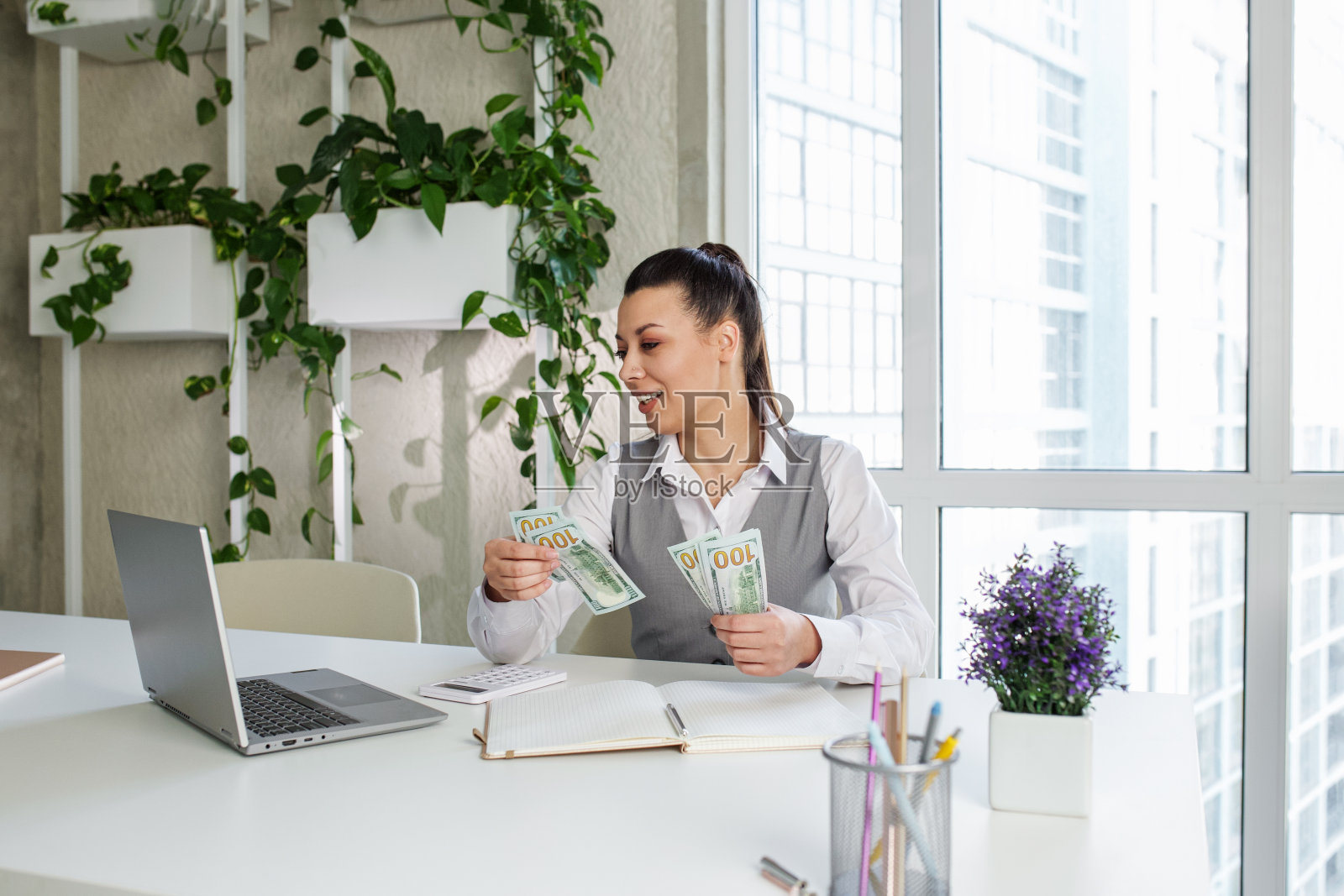 在现代办公室数钱的成功女性工作者。成就职业观照片摄影图片