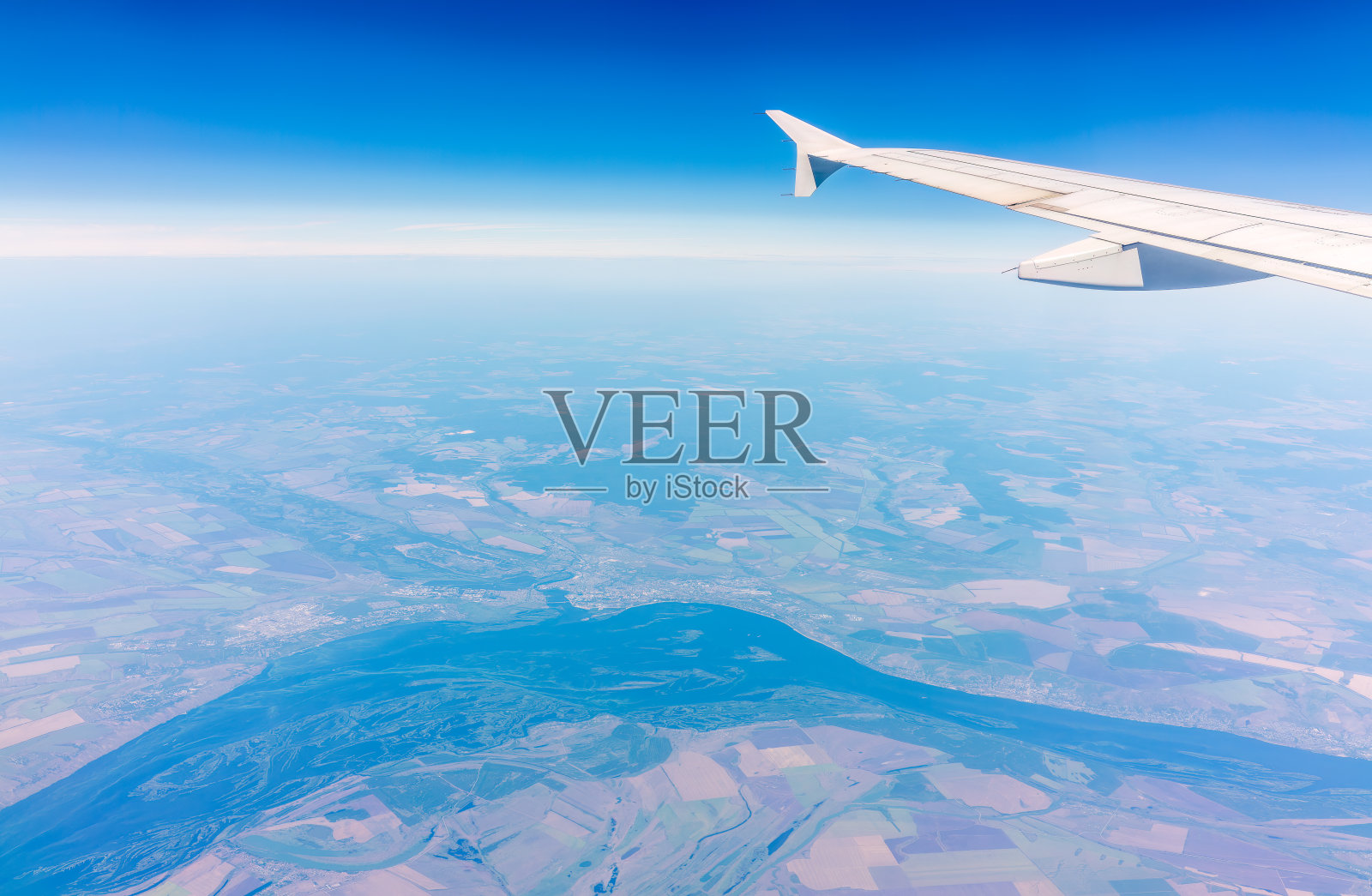 从飞机窗口俯瞰绿色地面。从飞机窗口看到日出时美丽的云照片摄影图片