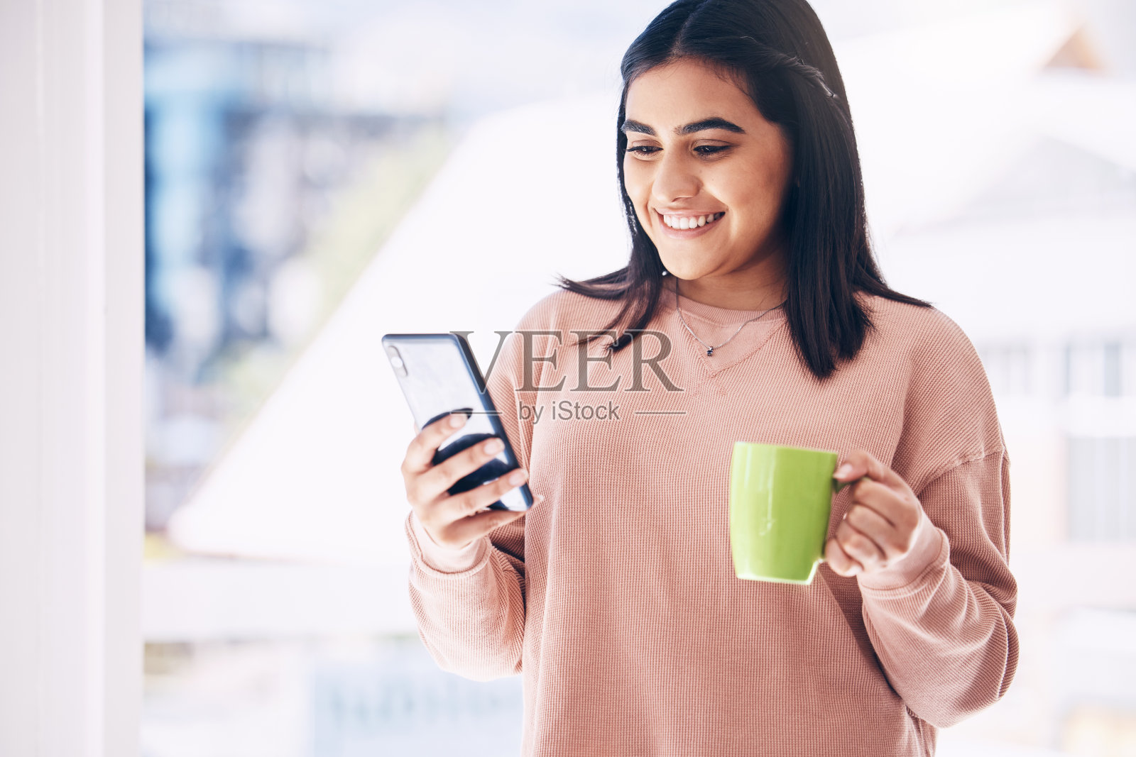 女人，打电话或在家里喝咖啡，家里或顶层公寓在社交媒体应用程序，互联网或约会网站。快乐的微笑，学生和放松的茶杯，移动博客或通讯技术照片摄影图片