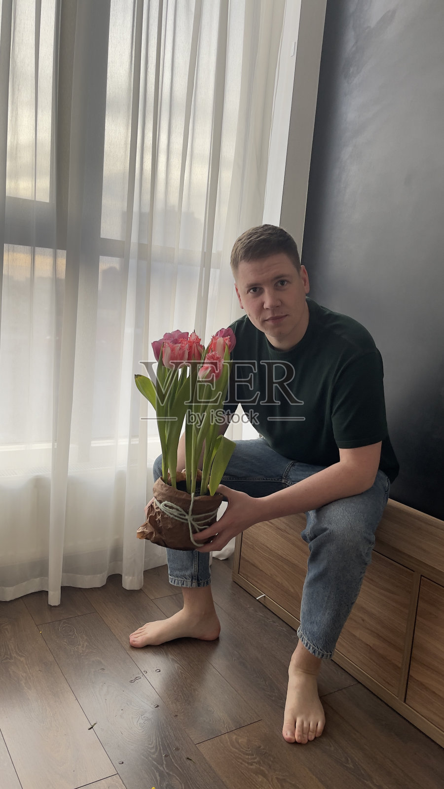 母亲节，鲜花郁金香，小伙子，情绪，欢笑，微笑，体贴，开朗，穿着绿色t恤，蓝色牛仔裤，双手，光着脚，小伙子，情绪，欢笑，微笑，体贴，开朗，穿着绿色t恤，蓝色牛仔裤，双手，光着脚照片摄影图片