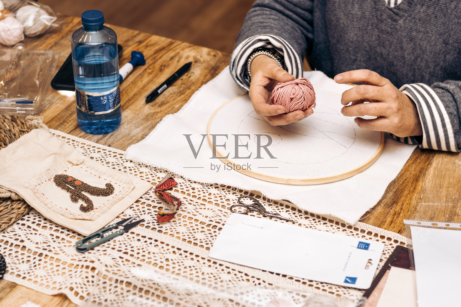 打孔针车间。中年妇女手里拿着一团毛线。照片摄影图片