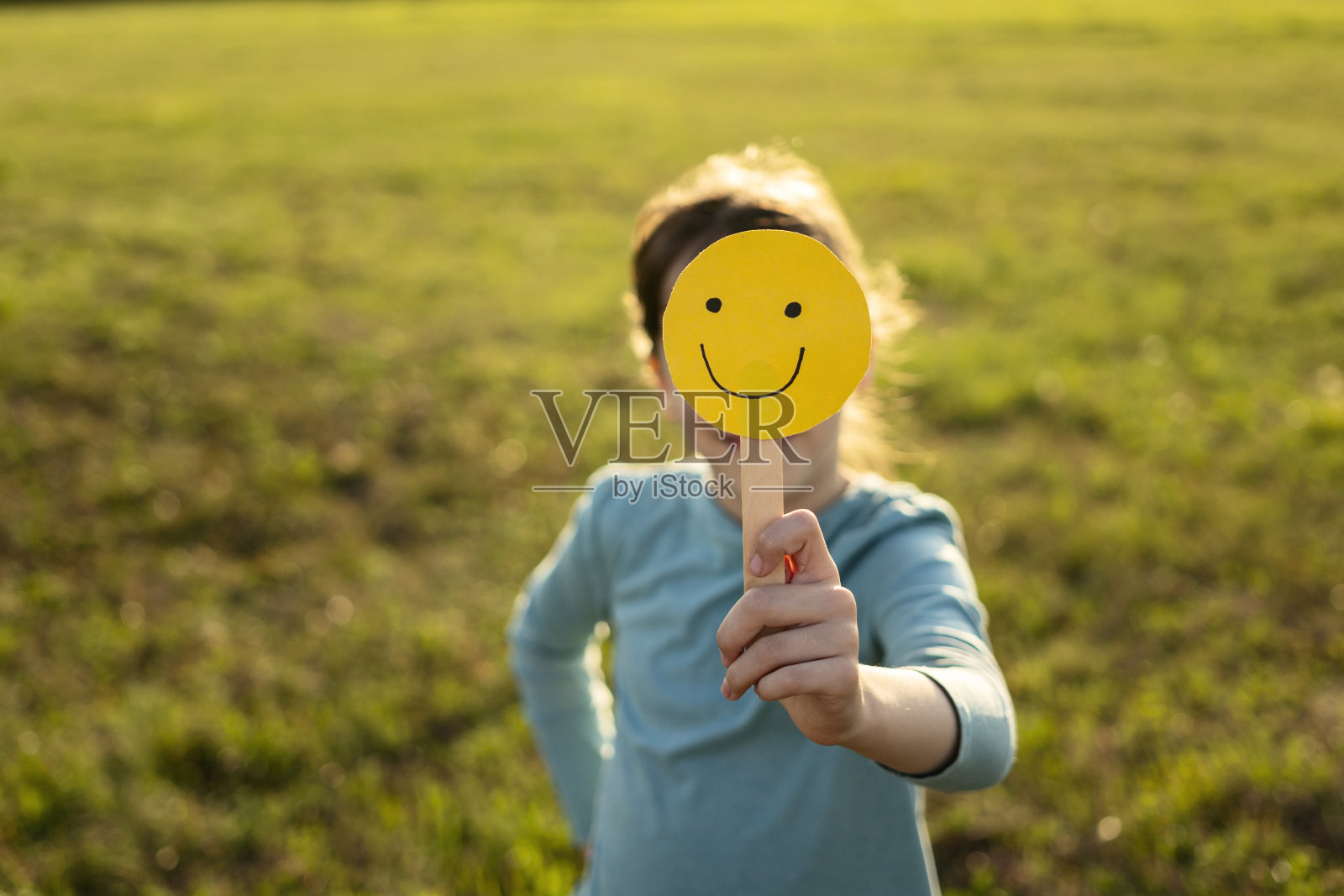 认不出来的孩子拿着表情符号微笑掩面照片摄影图片