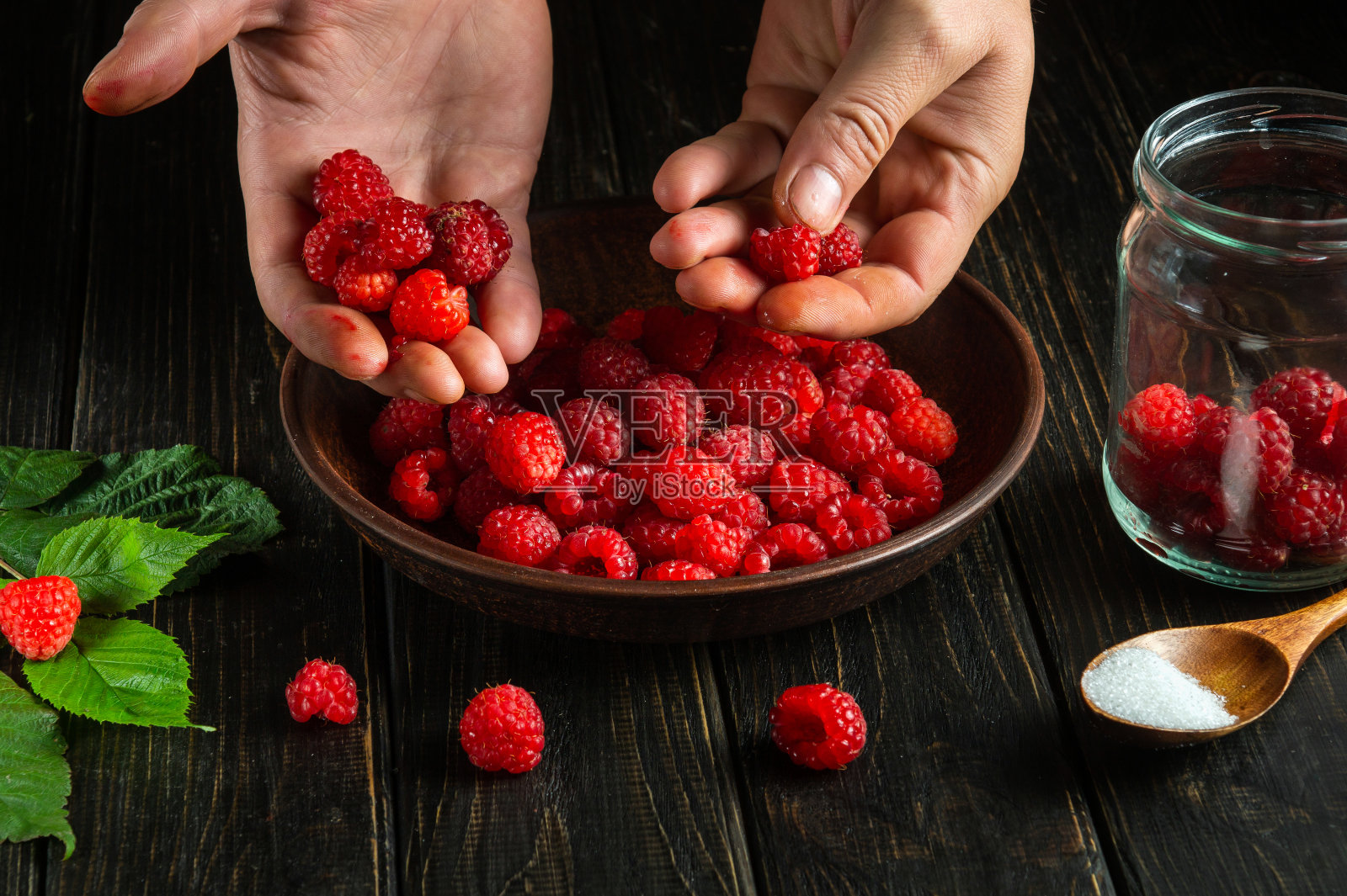 厨师正在厨房里挑选新鲜的红覆盆子，准备一种甜的软饮料。烹饪减肥甜点。照片摄影图片