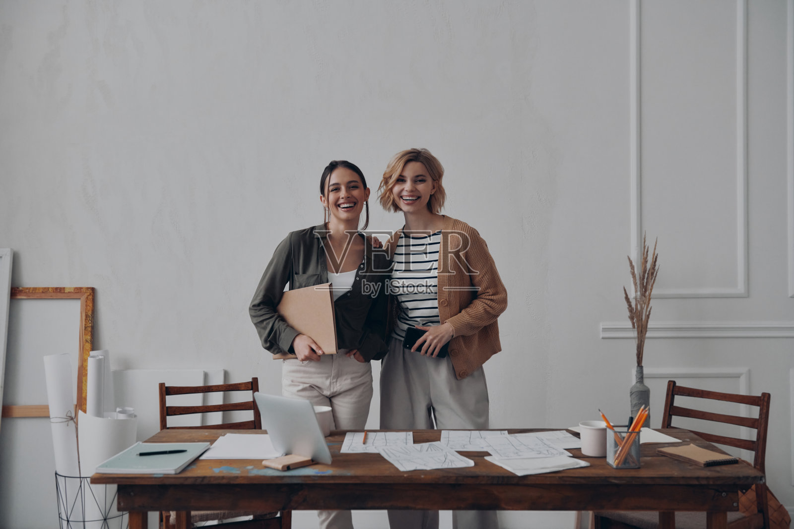 两个快乐的女同事站在她们富有创意的工作场所附近看着镜头照片摄影图片