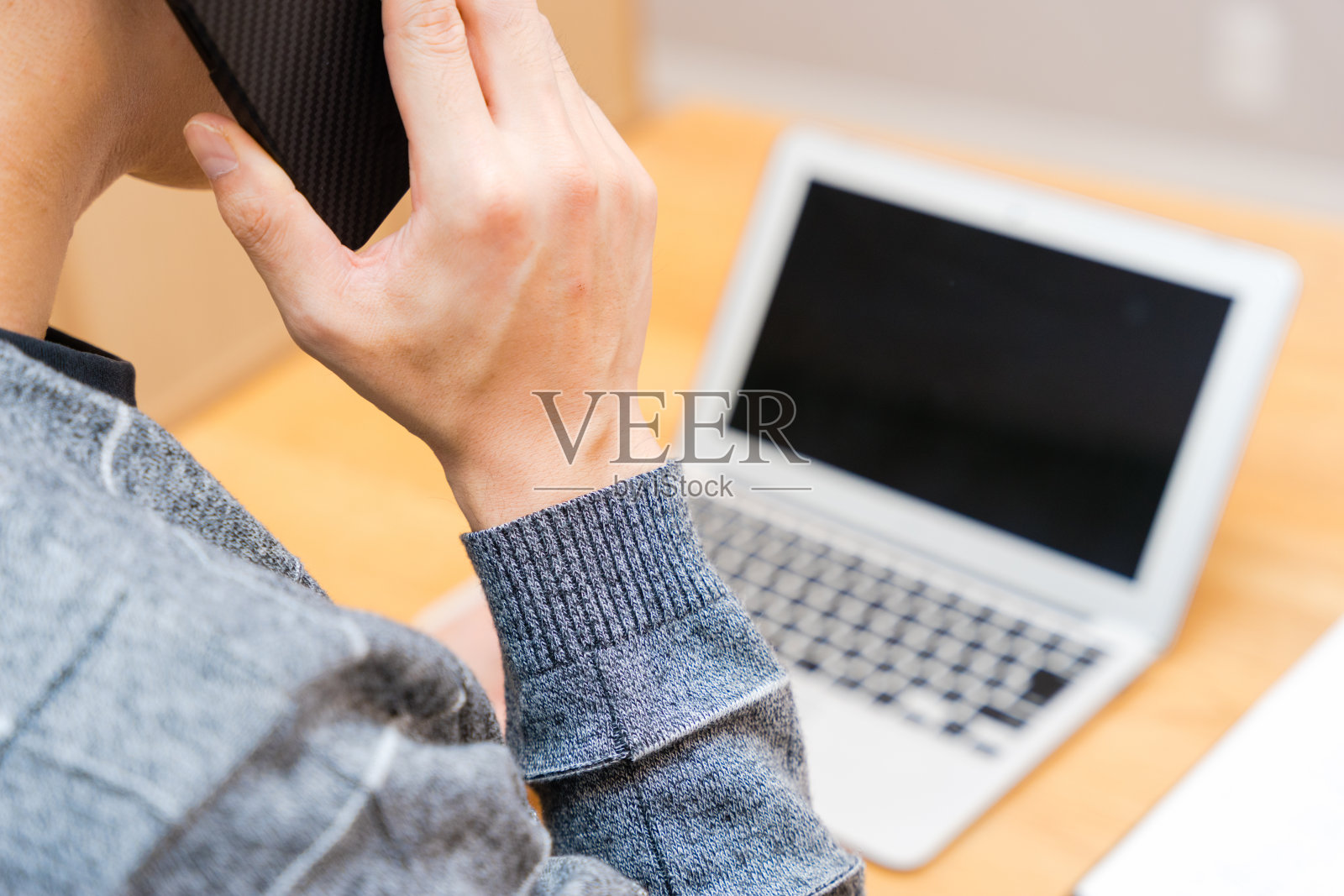 一个30多岁的男人的手在笔记本电脑前打电话照片摄影图片