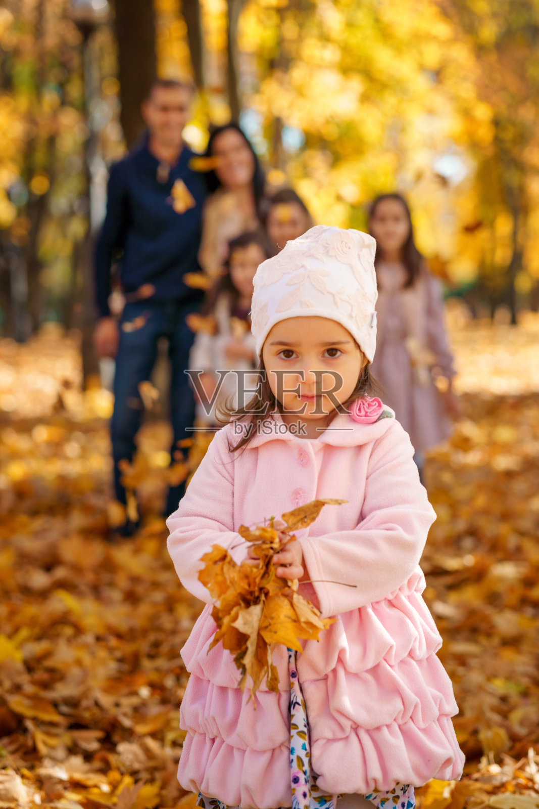 一个女孩和一个大家庭，孩子和父母在秋天的城市公园里的肖像，快乐的人们在一起摆姿势，美丽的大自然，明媚的阳光和黄色的树叶照片摄影图片
