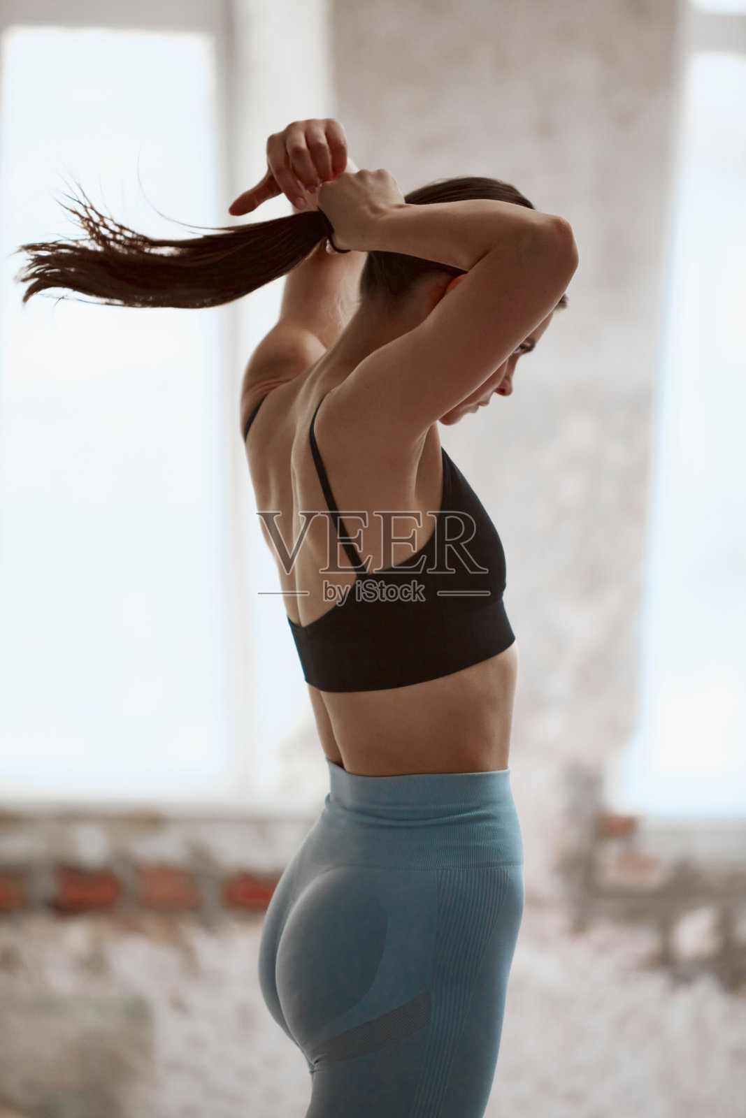 准备做练习。年轻活泼的女孩，穿着五颜六色的运动服，扎着马尾。白天进行室内训练照片摄影图片