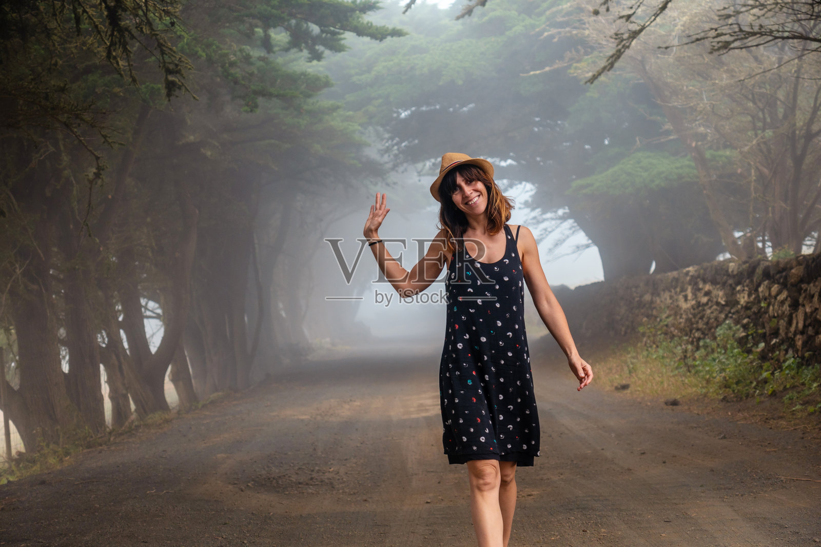 在耶罗，一名妇女漫步在雾蒙蒙的树林中，走向杜松林。加那利群岛照片摄影图片