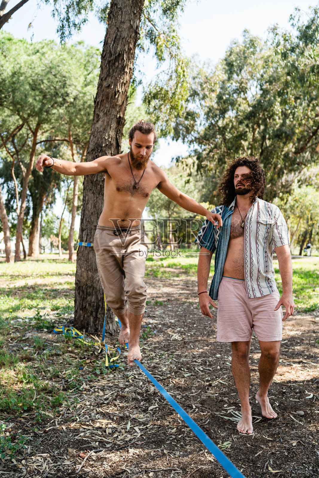 夏日里，两名男子在城市公园里滑滑梯照片摄影图片