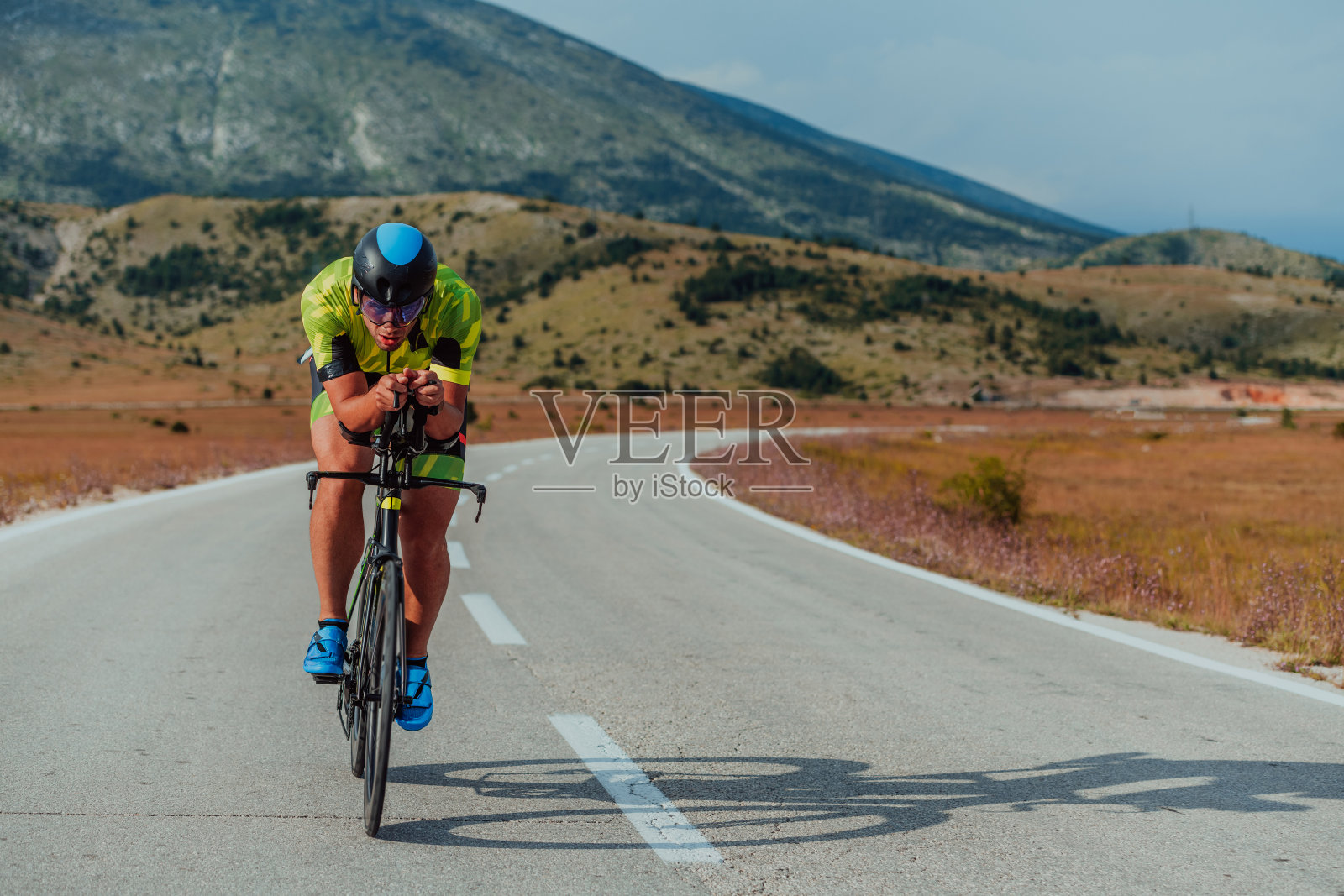一个穿着运动服、戴着防护头盔骑自行车的铁人三项运动员的全身画像。有选择性的重点照片摄影图片